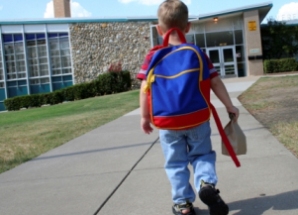 Child with backpack walking towards a school